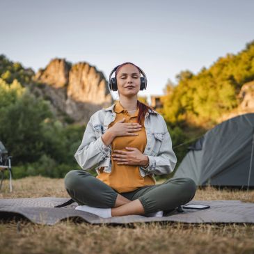 Woman meditating outdoors with headphones on.