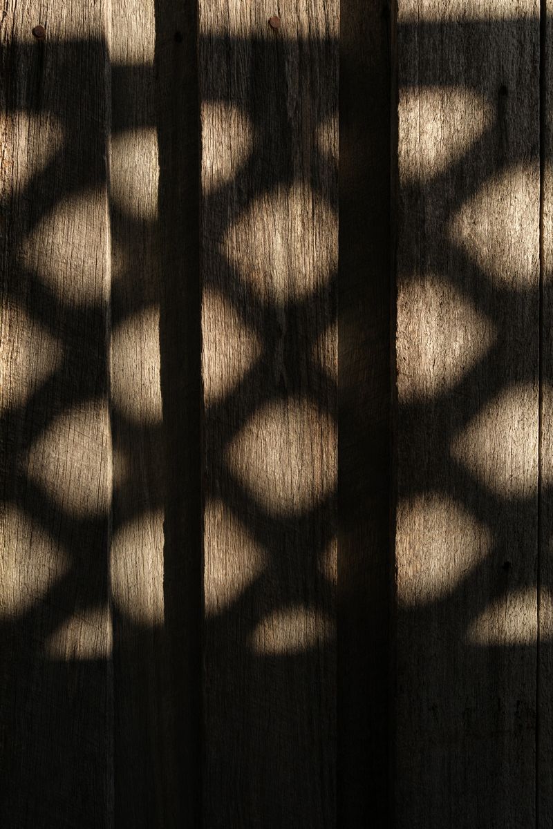 Criss cross shadow pattern on a wooden fence