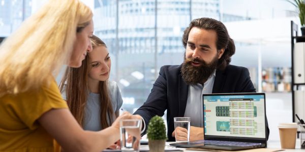 People discussing data on a laptop in an office.