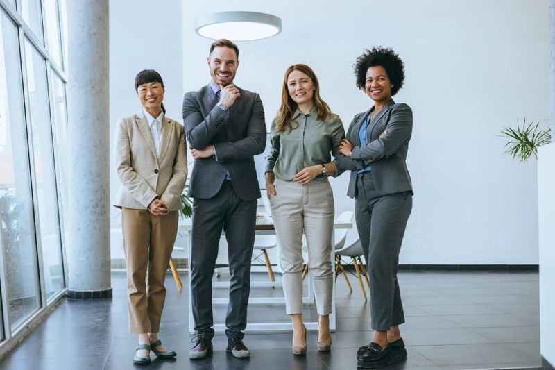 Smiling business team stands confidently in a modern office setting, representing teamwork and corporate unity in a professional atmosphere