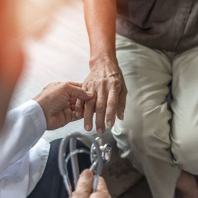 Doctor examining elderly patient's hand during a consultation.