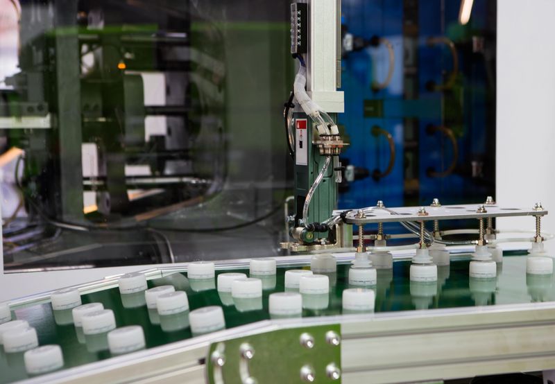 Plastic bottle caps on conveyor belt from plastic injection molding press machine. Industrial manufacturing.