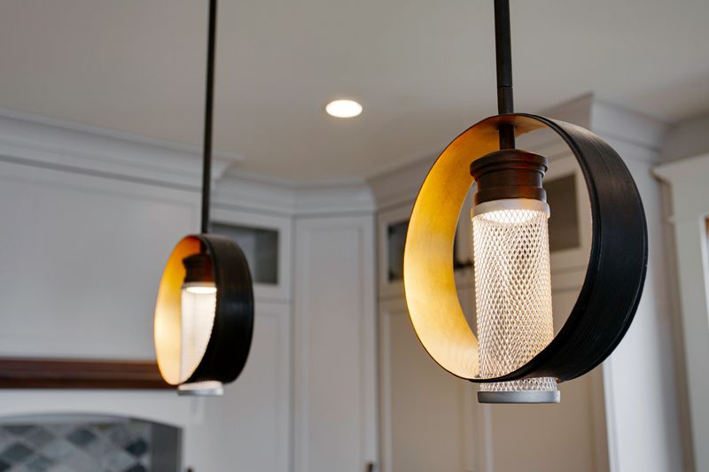 This image captures modern pendant lights with a unique circular design, illuminating a sleek and stylish kitchen space,these lights add a contemporary touch and serve as a significant decorative element, combining form and function seamlessly for a warm and inviting ambiance.