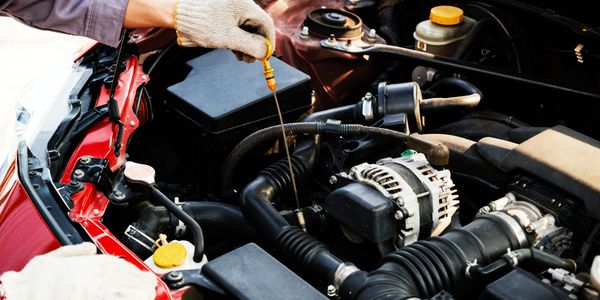 Person checking oil level in a car engine with a dipstick.