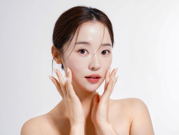 Young woman with clear skin touching her face.