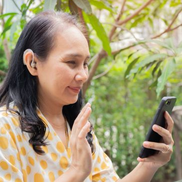 Woman using a smartphone for a video call outdoors.