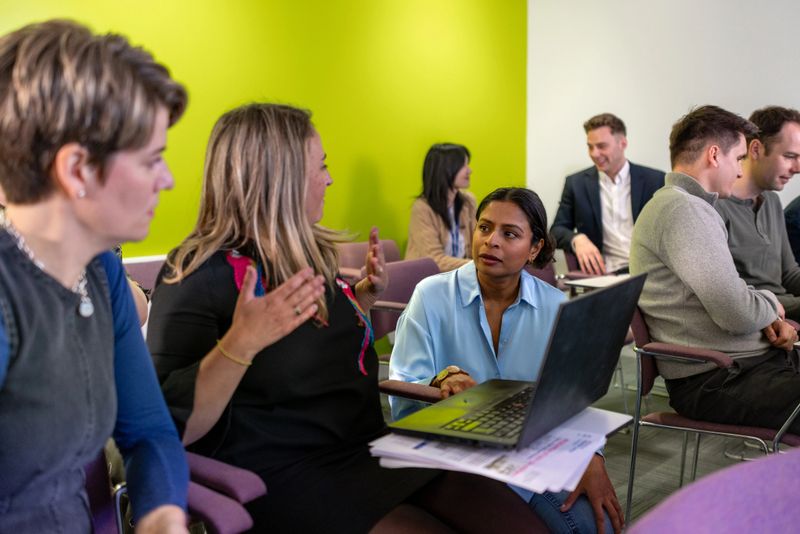 A wide shot of a university lecturer hosting a seminar for her colleagues and management team. The woman is kneeling next to a few of her colleagues and explaining the effects of personalised healthcare and optimising the microbiome in the gut.

Videos are available similar to this scenario.