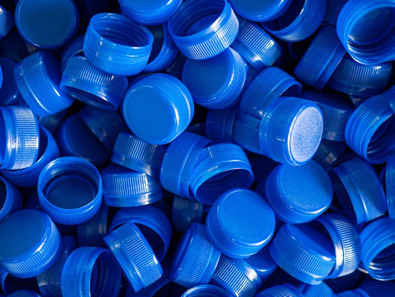 Top view blue plastic bottle caps.Recycling collection and production processing plastic bottle caps background ,Industrial production of bottle caps made of blue high-density polyethylene.