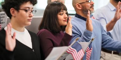 People taking an oath while holding American flags and documents.