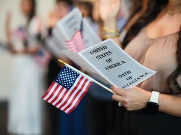 People holding American flags and reciting the United States Oath of Allegiance.