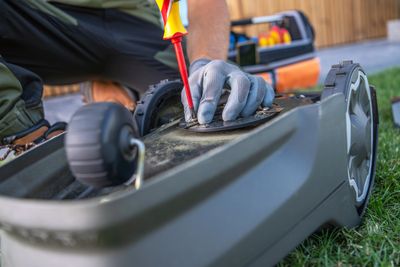 Person repairing a robotic lawn mower with a screwdriver.