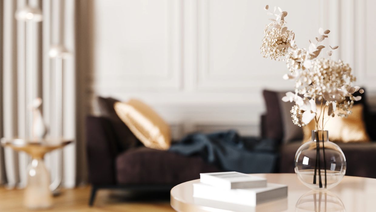 Dried flowers in a glass vase on a table in a cozy living room.