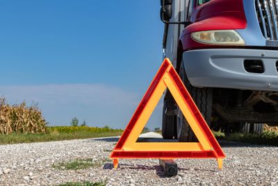 Emergency warning triangle placed in front of a stopped truck on a rural road.