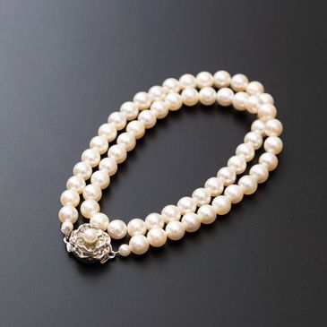 Elegant double-strand pearl necklace with a decorative clasp on black background.