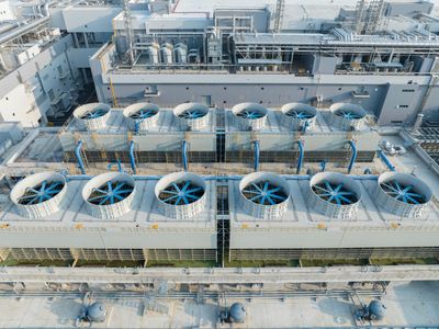 Aerial view of large industrial cooling fans on a factory rooftop.