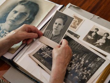 Hands holding black-and-white vintage portraits from a photo album.