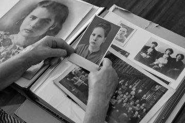 Hands holding an old black-and-white portrait over a photo album with vintage pictures.