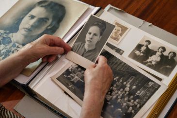 Hands holding an old black-and-white photo among several vintage photos.