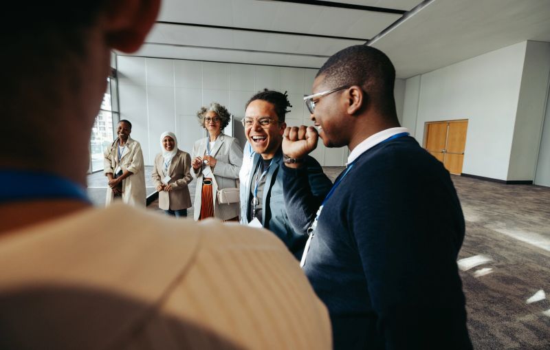 A group of joyful businesspeople laughing and engaging during a meeting in a modern office space. The atmosphere is friendly and collaborative.