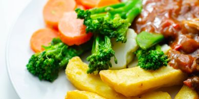 Plate of mixed vegetables with fries and meat.
