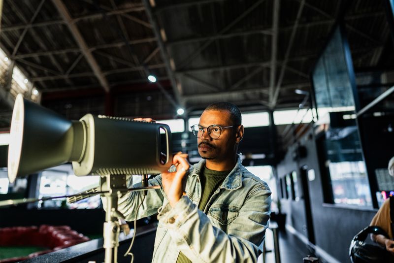Mid adult gay man using lighting equipment indoors