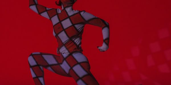 Person in a geometric patterned bodysuit against a red background.