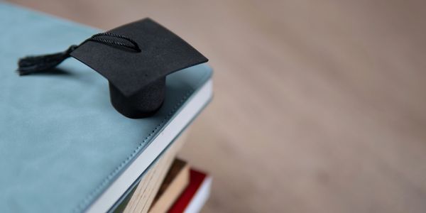 Miniature graduation cap on a stack of books symbolizing education.