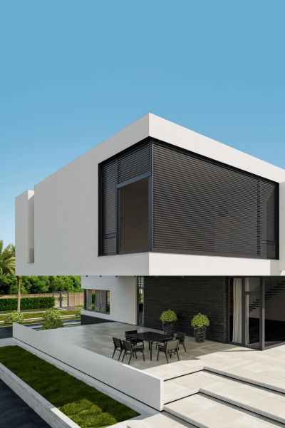 Modern white two-story house with outdoor seating area.