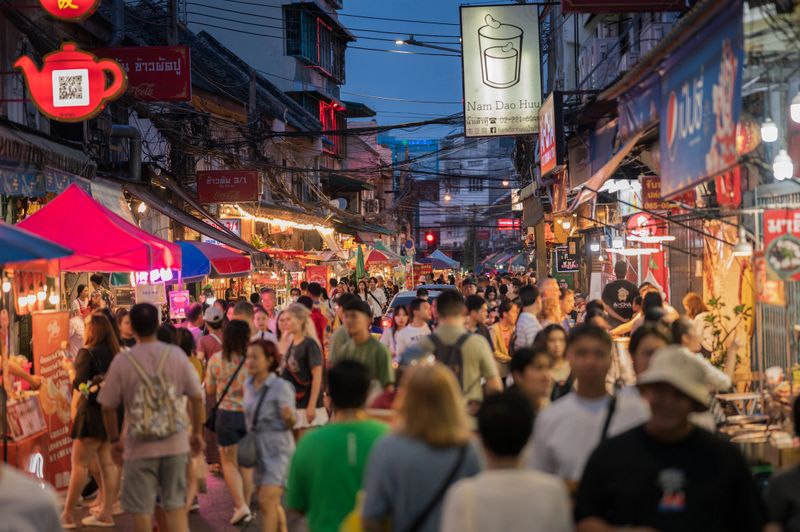 A wide-angle shot of tourists and locals enjoying the famous street food in Yaowarat, Bangkok. Great for highlighting the culinary delights and diverse crowd of Chinatown.