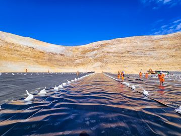 Workers installing geotextile liner in a large excavation site.