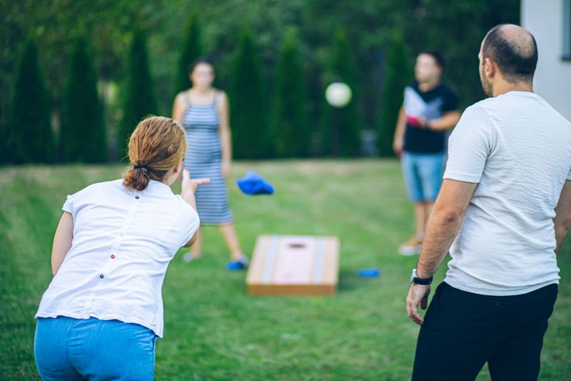 Best friends playing bean bag toss in the backyard