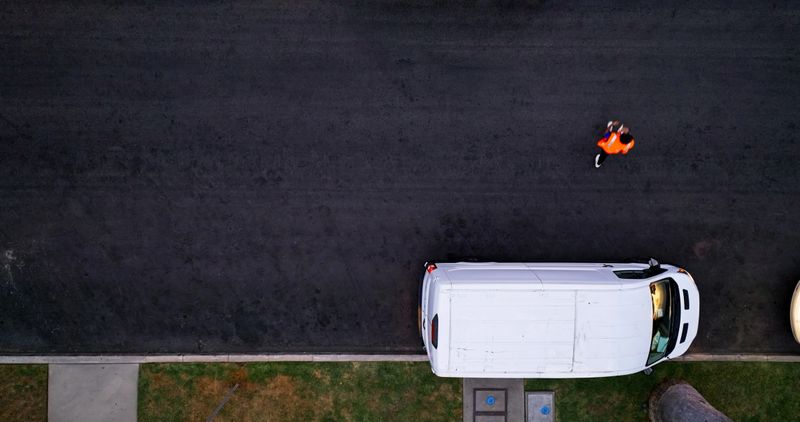 Aerial shot directly above a white delivery van on a residential street in Los Angeles, California.