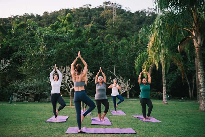 Group of women having a Yoga class outdoors with a instructor