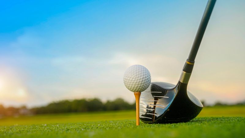 Golf clubs and balls on a green lawn in a beautiful golf course with morning sunshine. Close up of golf equipment on green grass.
