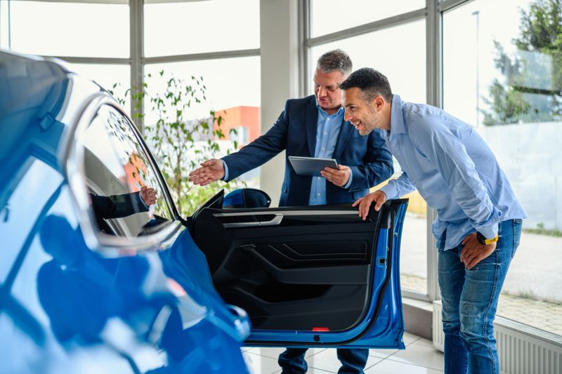 Salesman helping the male customer to choose a new car
