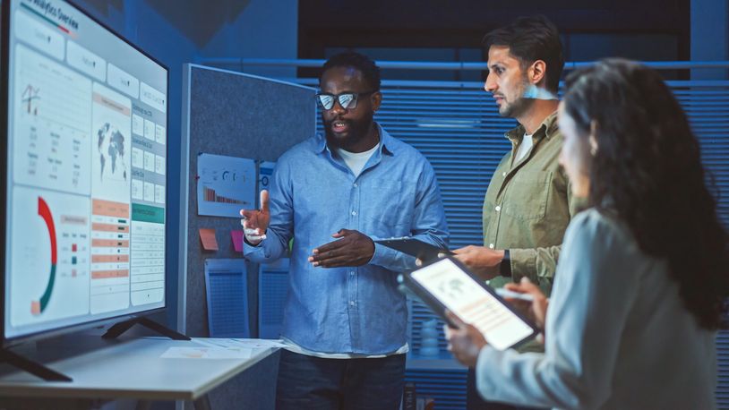 Team discussing data on a large screen in an office.