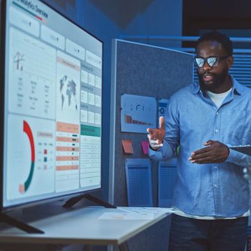 Man presenting data on a large screen in an office.
