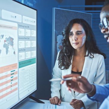 Two professionals analyzing data on a large screen in an office.
