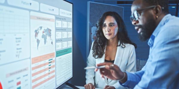 Two professionals analyzing data on a large screen.