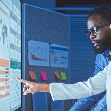 Two professionals analyzing data on a large touchscreen display.