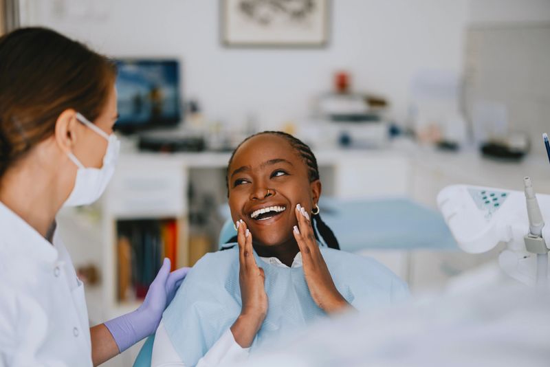 A cheerful patient expressing joy after a successful dental checkup at a modern clinic, attended by a smiling dentist.