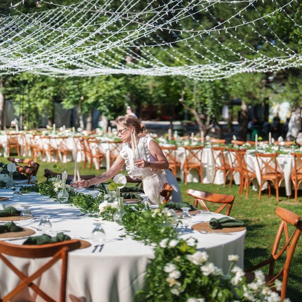 Woman setting candles on an elegantly decorated outdoor wedding table.