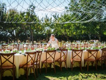 A woman arranging outdoor tables under string lights for an event.