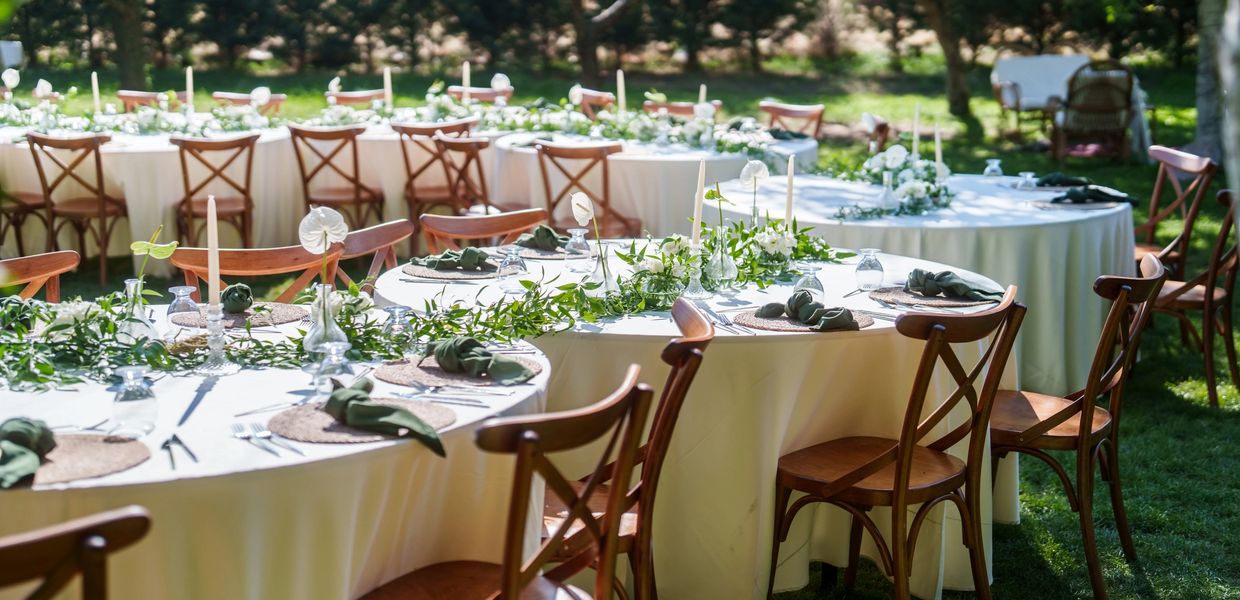 Elegant outdoor wedding reception tables with white tablecloths and floral centerpieces.