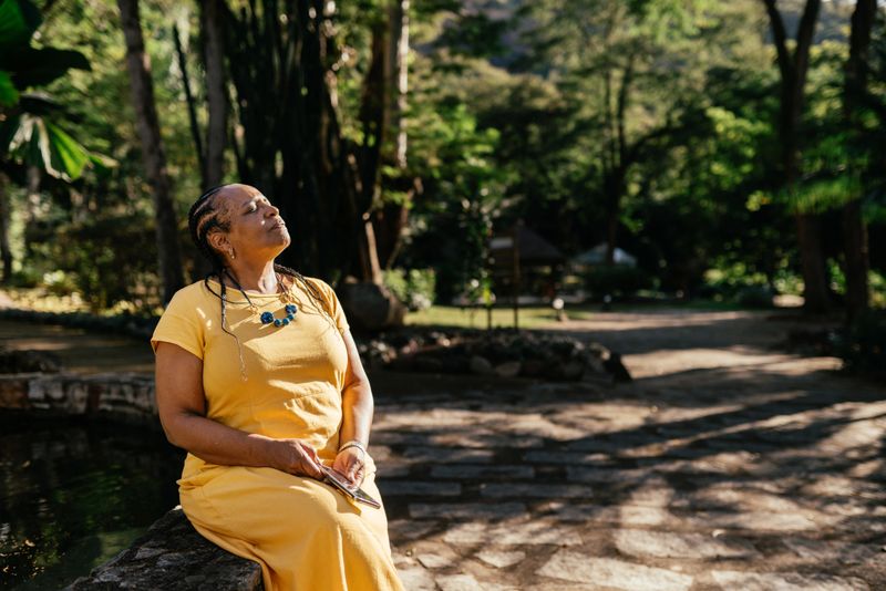 Portrait of a beautiful mature woman relaxing and enjoying a beautiful garden in a sunny day, in a luxury spa during holidays