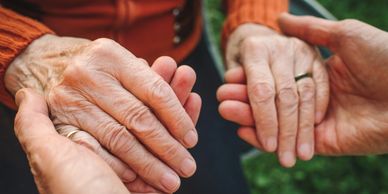 Elderly couple holding hands, showing love and support.