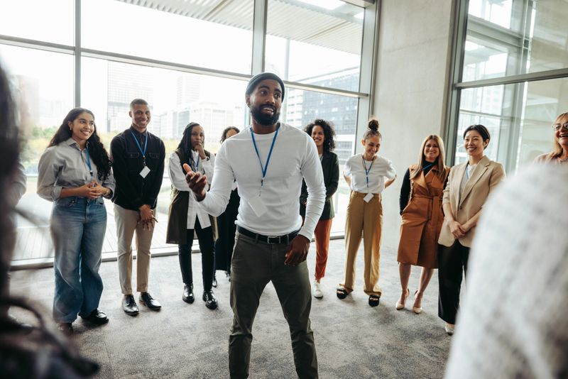 Confident businessman leading an engaging team-building session with a diverse team in a modern office environment, fostering communication and collaboration.