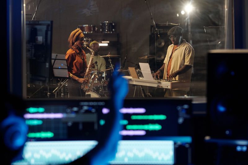 Musicians engaging in live music production in professional recording studio surrounded by equipment creating diverse sound