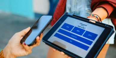 Person holding a smartphone near a tablet showing a survey.