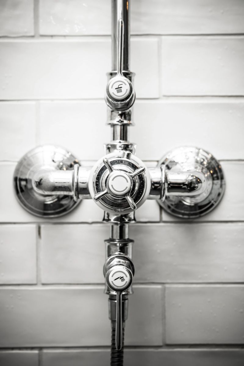 Stylish chrome shower control system mounted on a wall of sleek white subway tiles. Perfect for modern bathrooms and interior design inspiration.